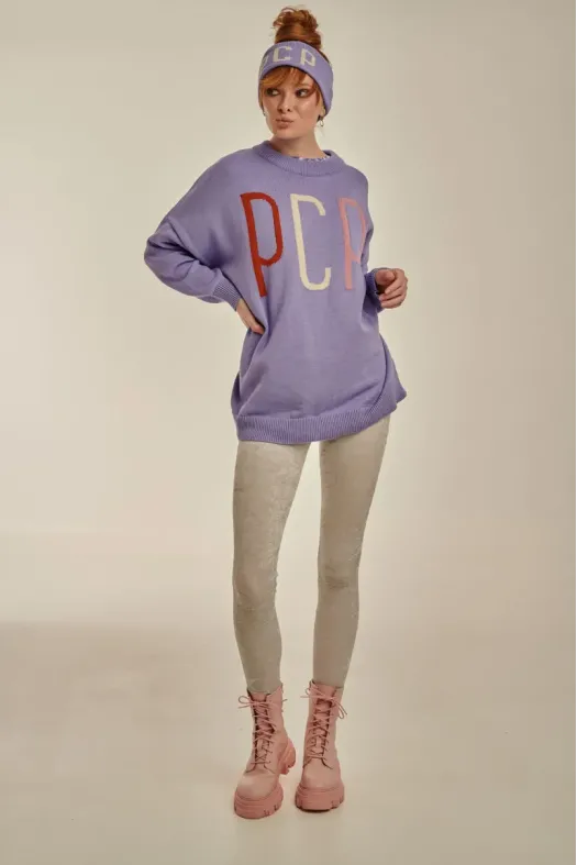 Person wearing a purple sweatshirt with 'PCP' on it, beige leggings, and pink boots against a neutral background.