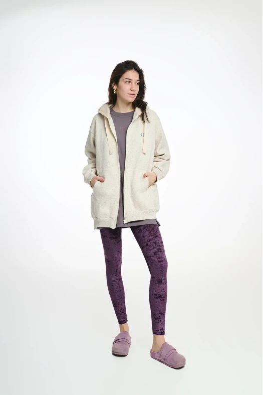 Person wearing a cream hoodie and purple leggings on a white background