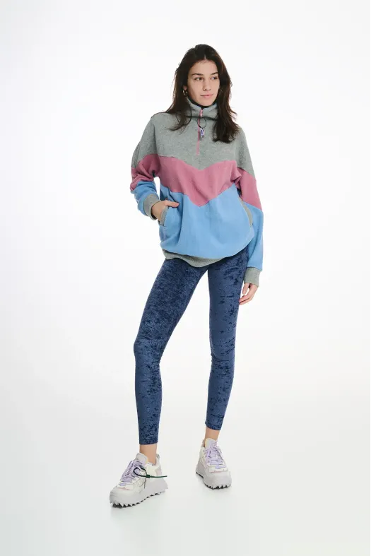 Woman wearing a colorful hoodie and blue leggings on a white background