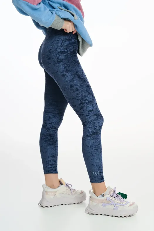 Person wearing blue acid-wash leggings with sneakers on a white background