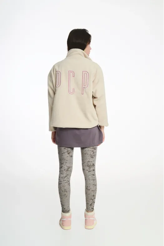 Person wearing a beige jacket with 'P.C.P.' on the back, gray leggings, and pink shoes on a white background