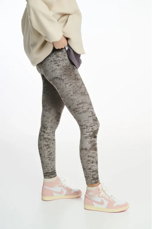 Person wearing gray marbled leggings with a cream sweater and pink Nike sneakers on a white background