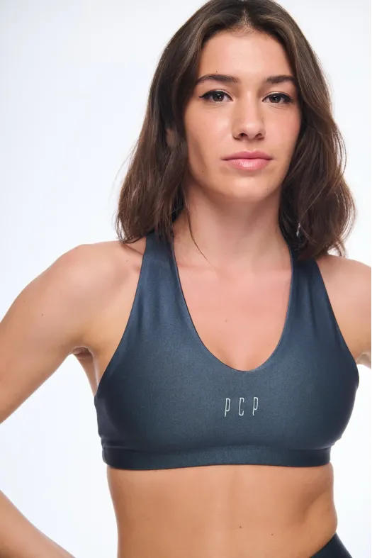 Woman wearing a blue sports bra with 'PCP' branding on a white background