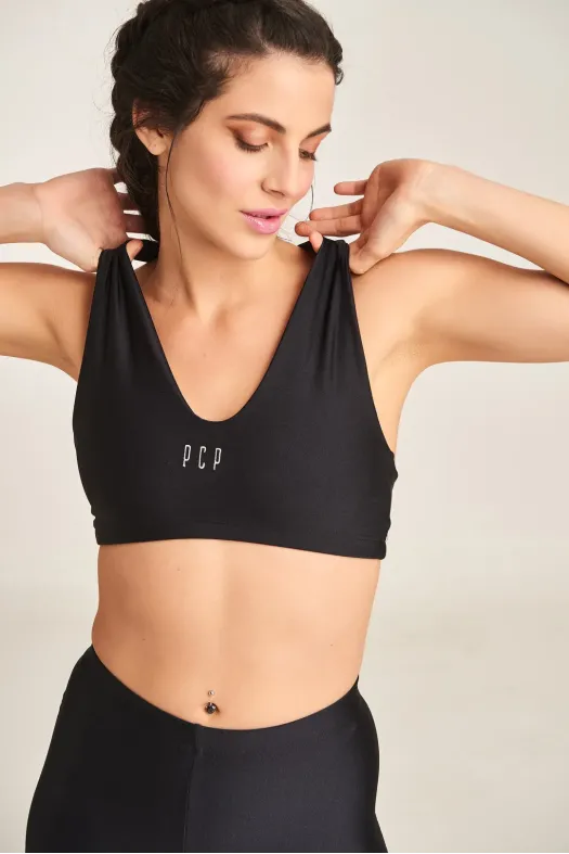 Woman wearing a black sports bra with 'PCP' branding on a plain background