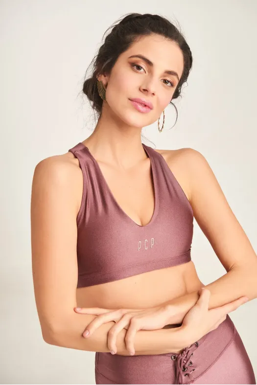 Woman wearing a mauve sports bra and leggings with 'FCB' branding on a light background