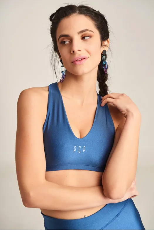 Woman wearing a blue sports bra with 'PCP' branding against a neutral background