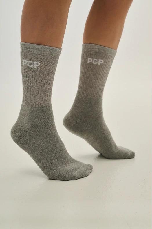 Gray socks with 'PCP' branding worn by a person on a light gray
