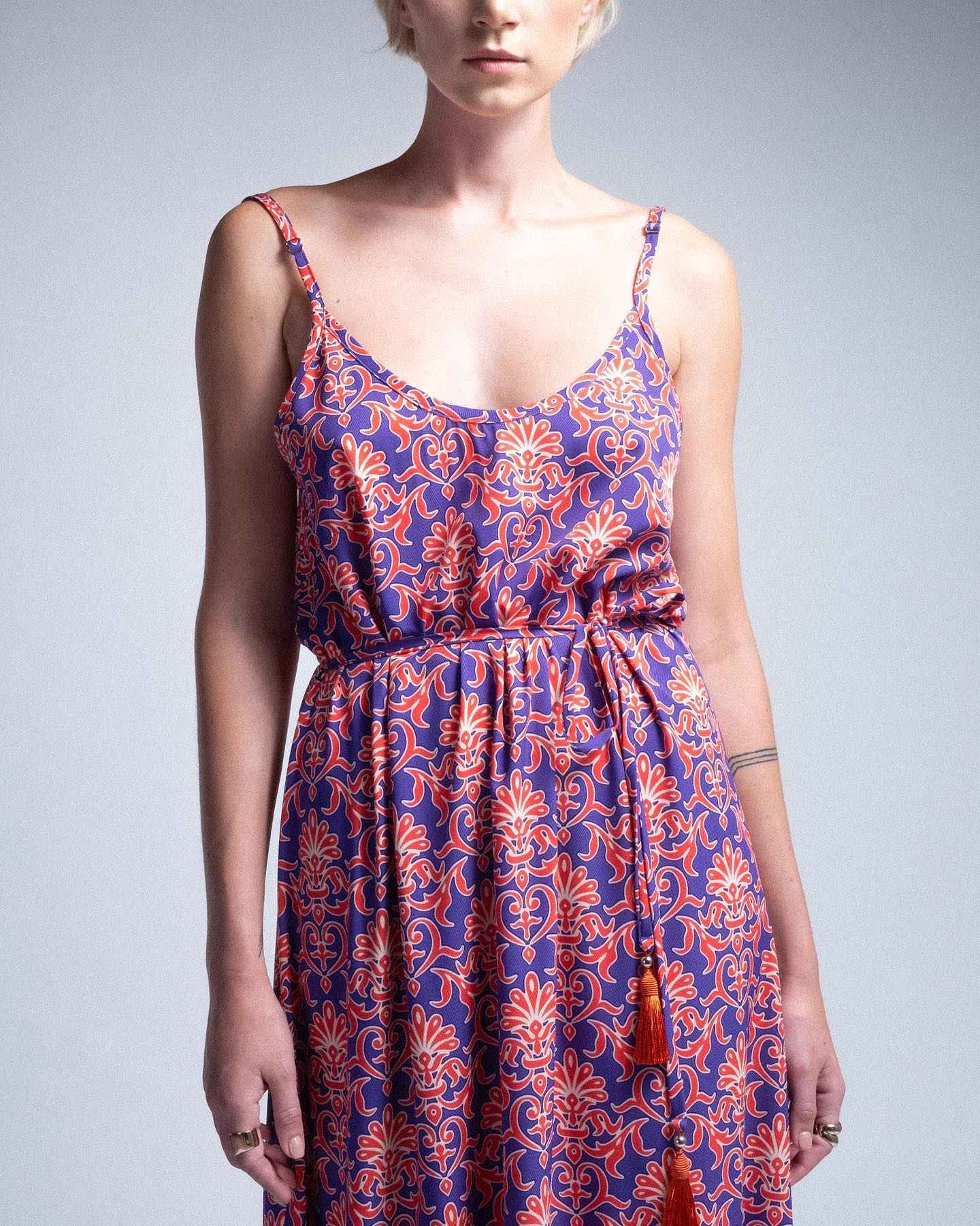 Woman wearing a blue and orange patterned dress against a gray background