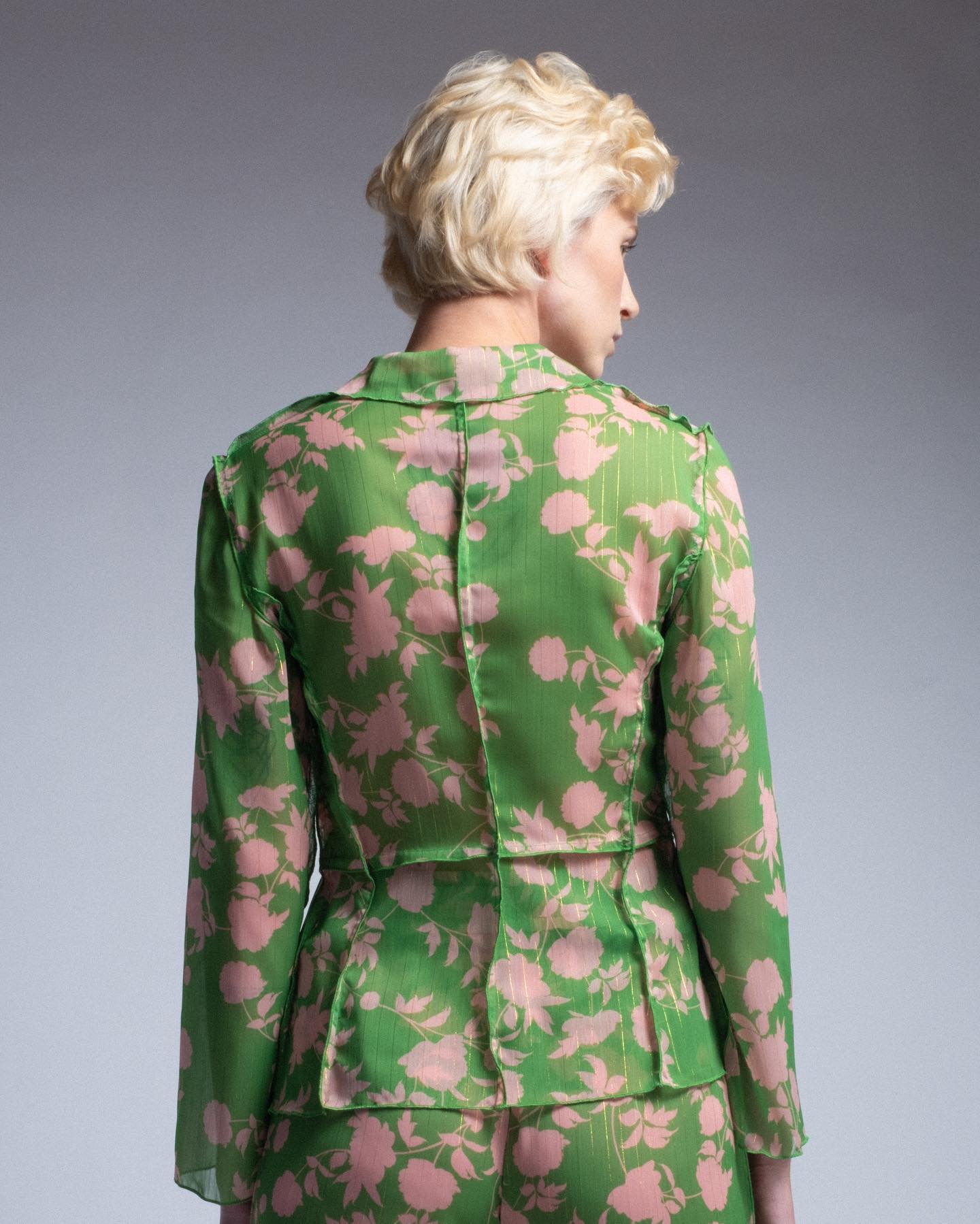 Person wearing a green floral suit against a gray background