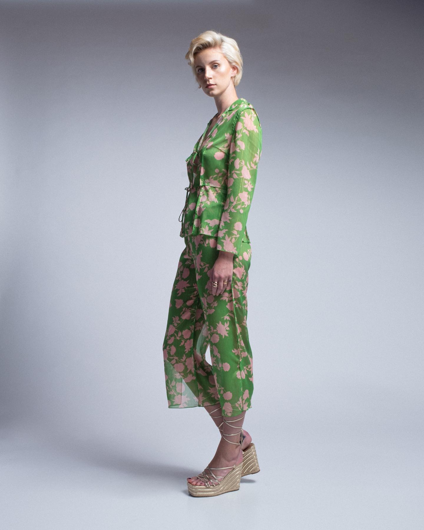 Woman wearing a green floral jumpsuit on a gray background