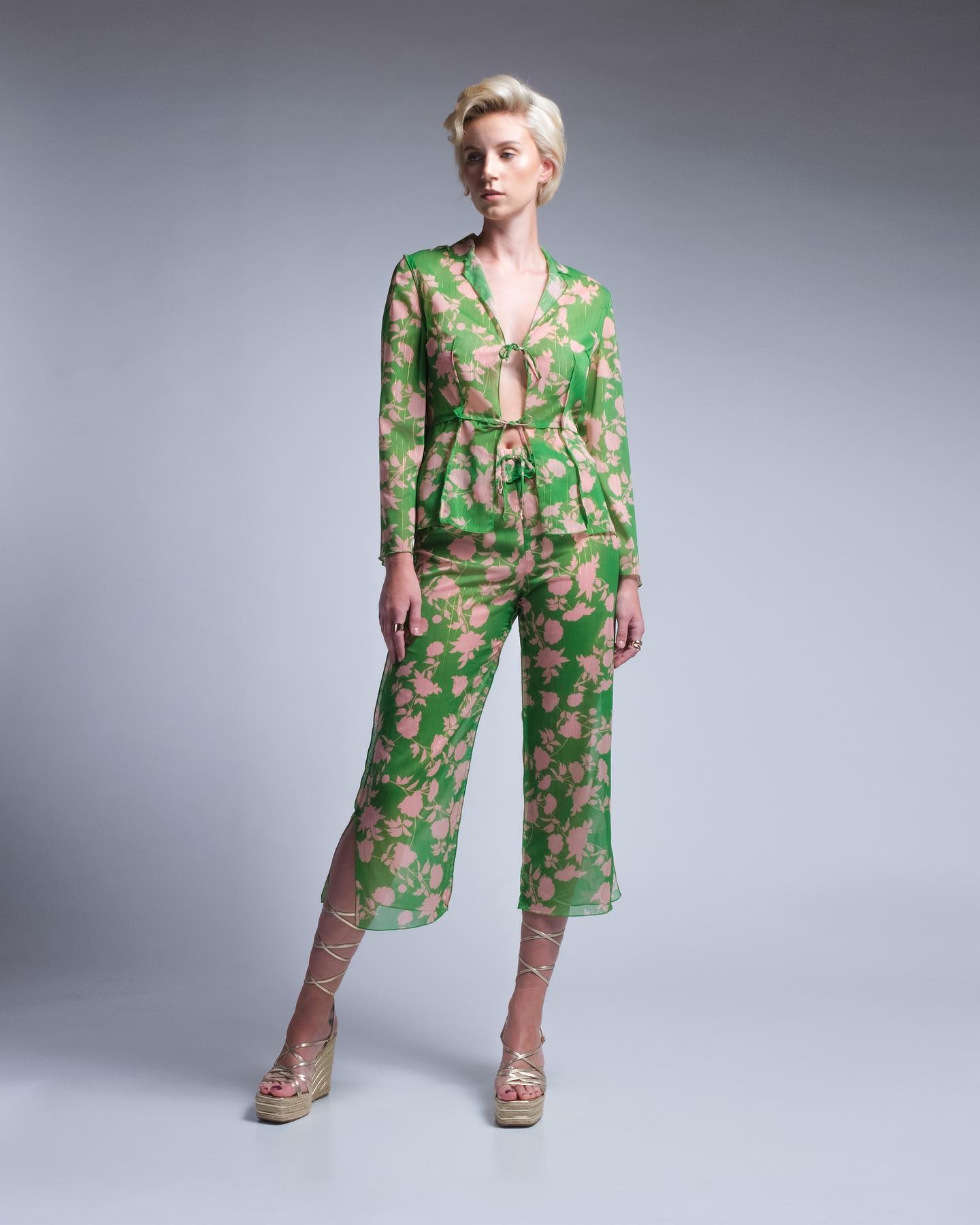 Woman wearing a green floral suit on a gray background
