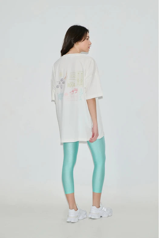 Person wearing a white oversized shirt and turquoise leggings on a plain background