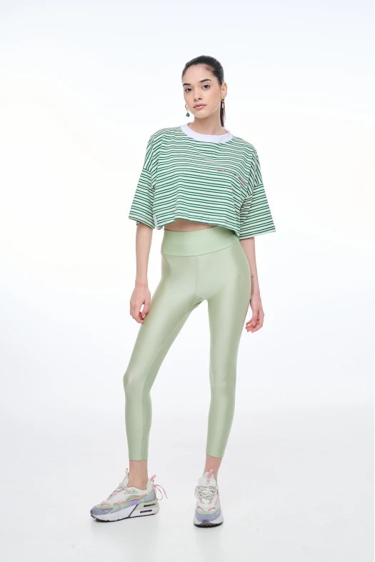Person wearing a green and white striped crop top and light green leggings on a white background