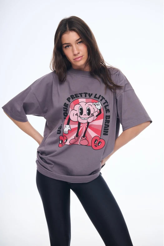 Woman wearing a gray oversized t-shirt with a graphic design on a white background