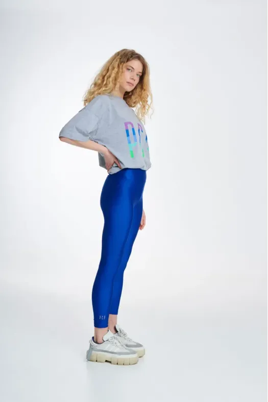 Woman wearing a gray sweatshirt with colorful graphics and blue leggings on a white background