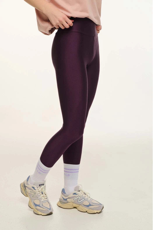 Person wearing maroon leggings with a neutral background