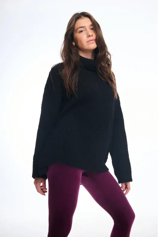 Person wearing a black sweater and purple pants on a white background