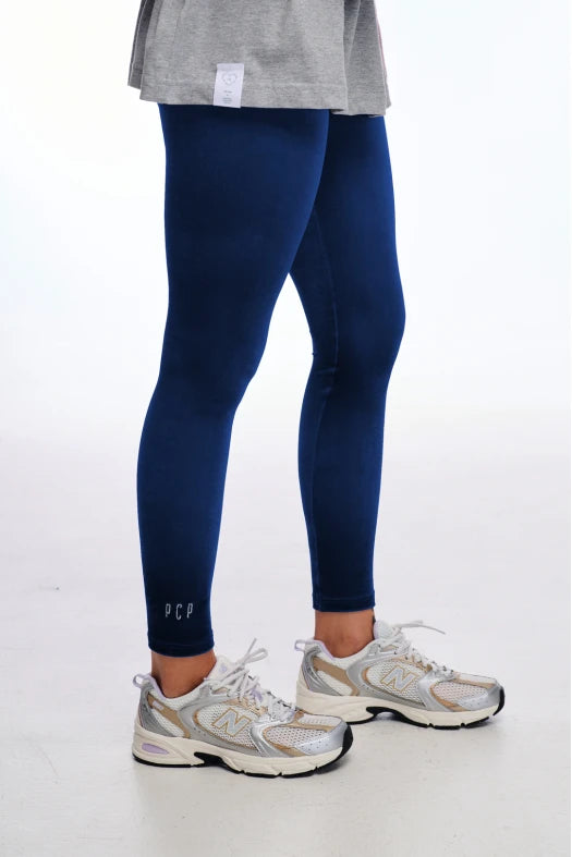 Person wearing navy leggings with white text and gray sneakers on a white background