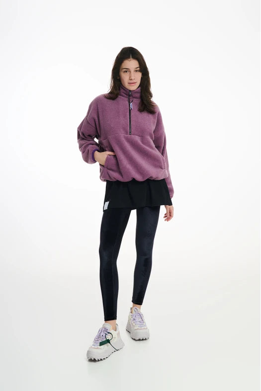 Person wearing a purple fleece pullover and black leggings on a white background