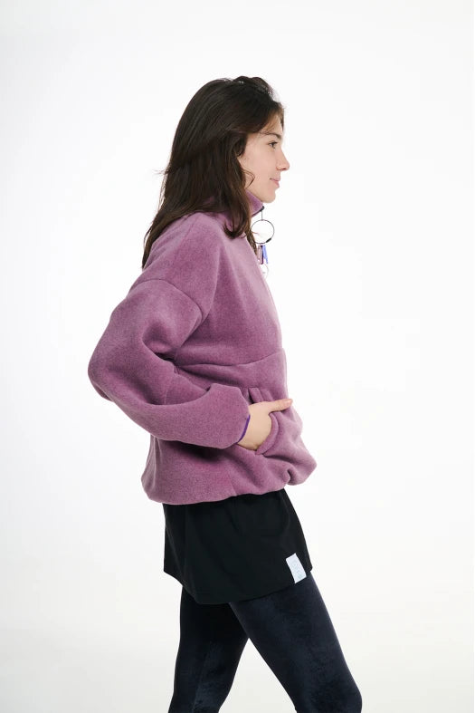 Person wearing a purple sweater and black pants on a white background