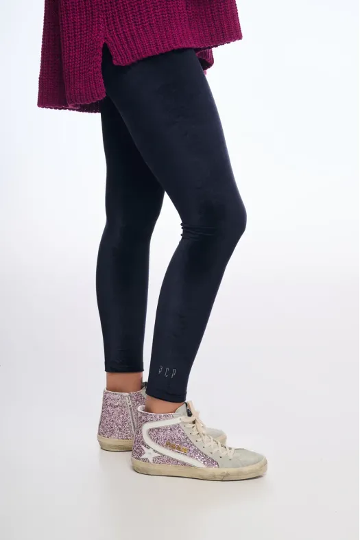 Person wearing black leggings with a purple coat and glittery sneakers on a white background