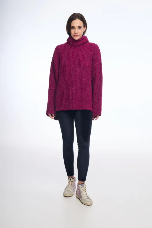Person wearing a magenta sweater, black leggings, and beige shoes on a white background
