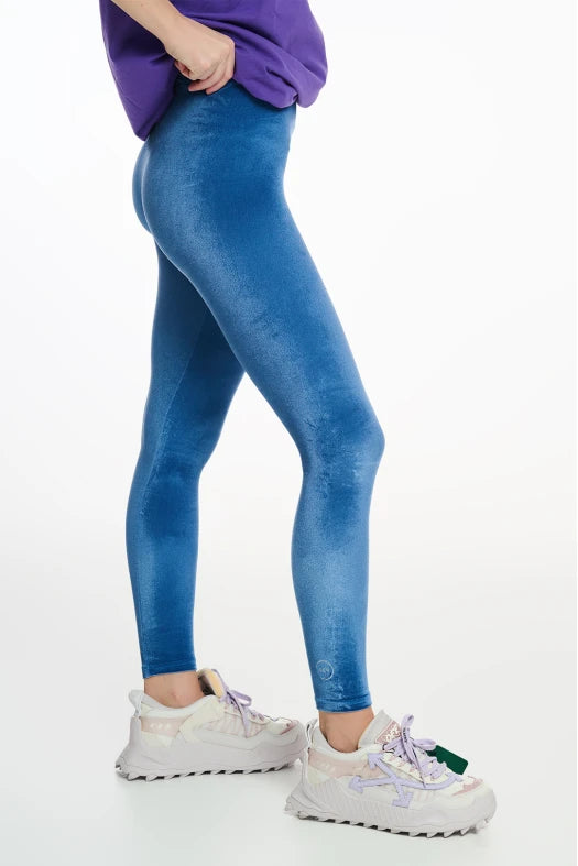 Person wearing blue jeans and white sneakers on a white background