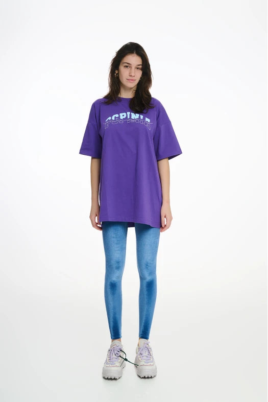 Person wearing a purple oversized t-shirt and blue leggings on a white background