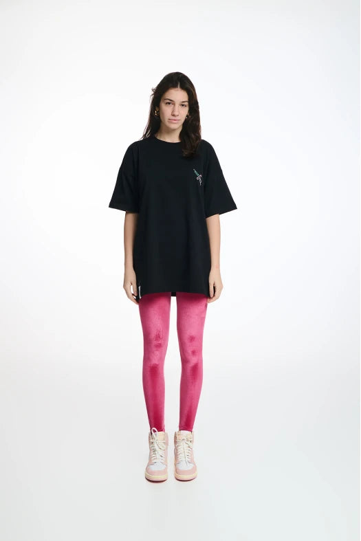 Person wearing a black oversized t-shirt and pink leggings on a white background