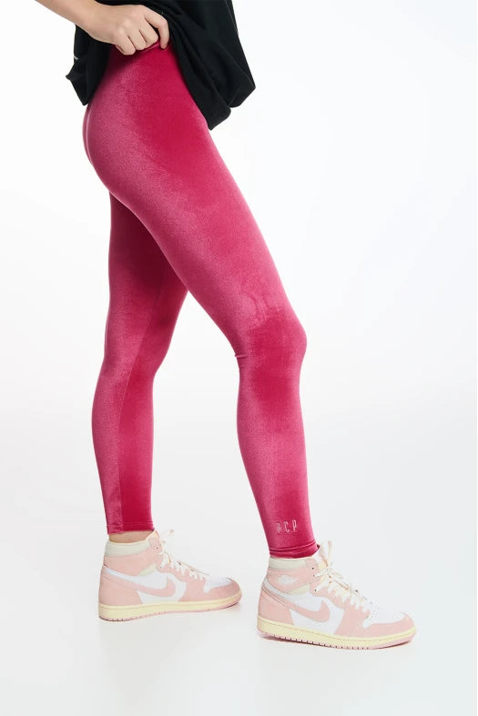 Person wearing bright pink leggings and white sneakers on a light gray background