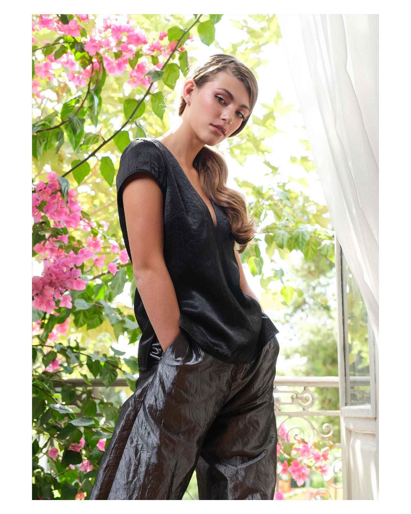 Woman wearing a black outfit with floral and window background