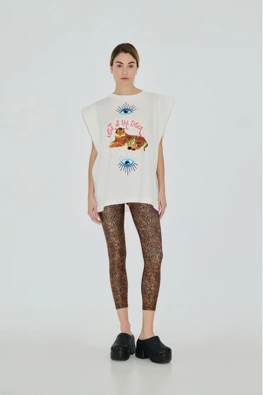 Person wearing a sleeveless graphic top and patterned leggings on a white background