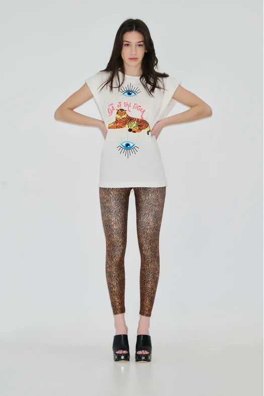 Woman wearing a graphic t-shirt and patterned leggings on a white background