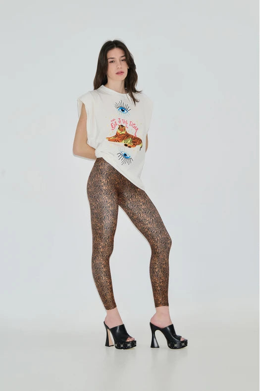 Woman wearing a white sleeveless top with graphics and patterned leggings on a white background