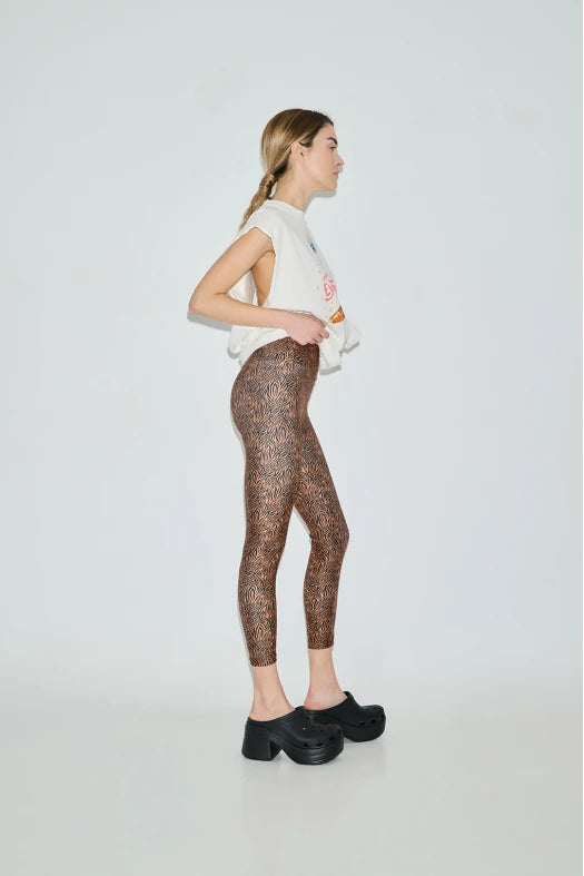 Woman wearing patterned leggings and a white top on a plain background