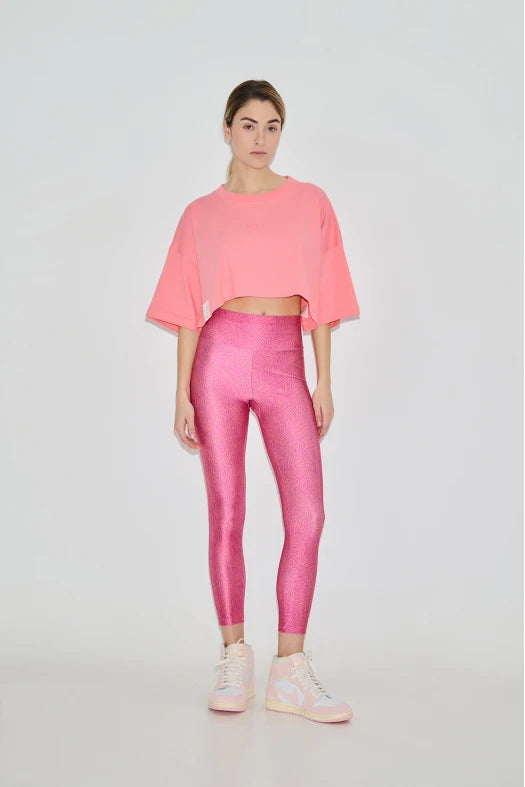 Woman wearing a pink outfit with a top and leggings on a white background