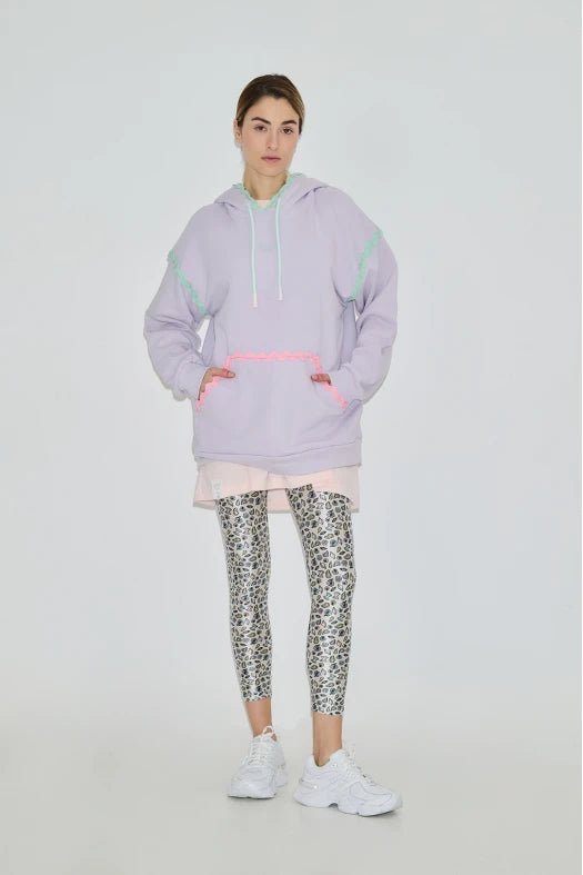Person wearing a light purple hoodie and patterned leggings on a white background