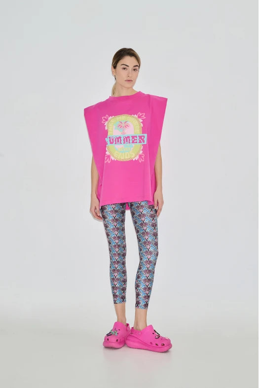 Person wearing a bright pink oversized top with a graphic design and patterned leggings on a white background