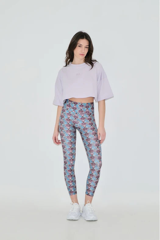 Woman wearing a light purple cropped top and patterned leggings on a white background
