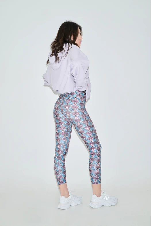 Woman wearing a white sweatshirt and patterned leggings on a white background