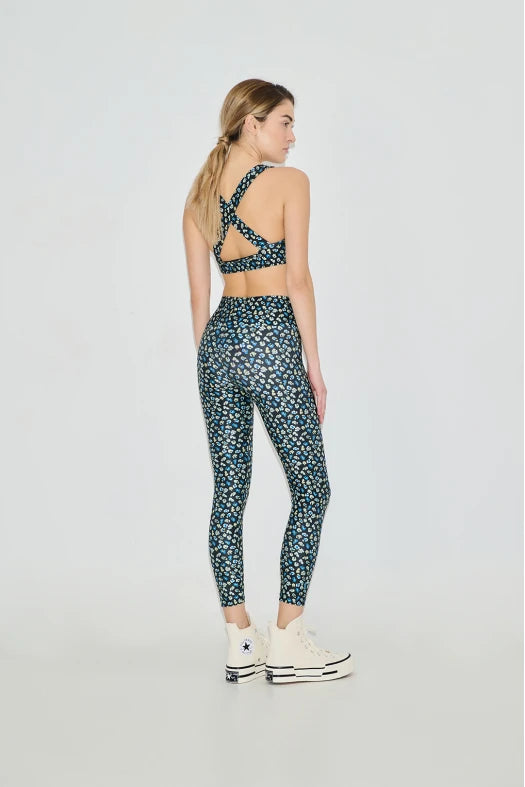Woman wearing a patterned sports bra and leggings set on a white background