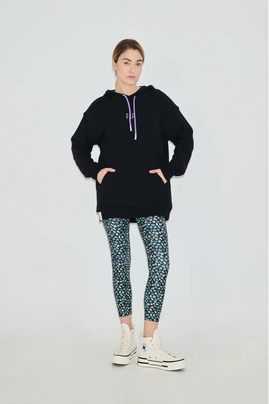 Person wearing a black hoodie and patterned leggings on a white background