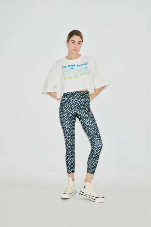 Person wearing a white graphic t-shirt and patterned leggings on a white background