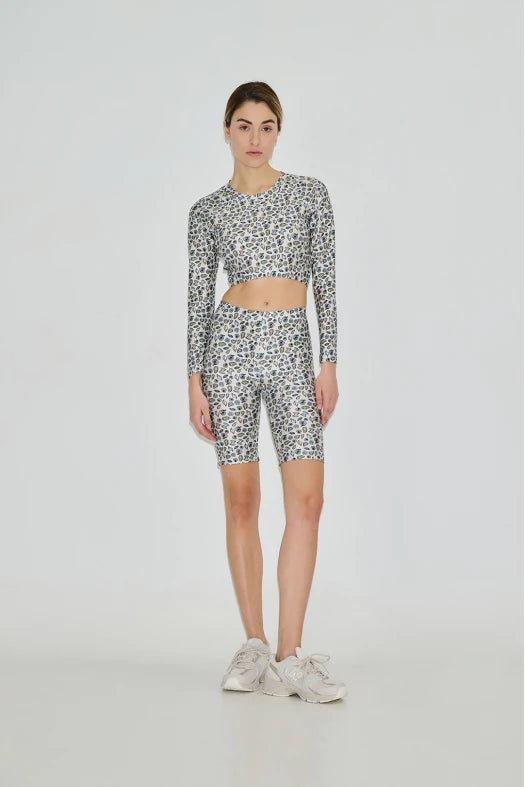 Person wearing a patterned long-sleeve top and bike shorts on a white background