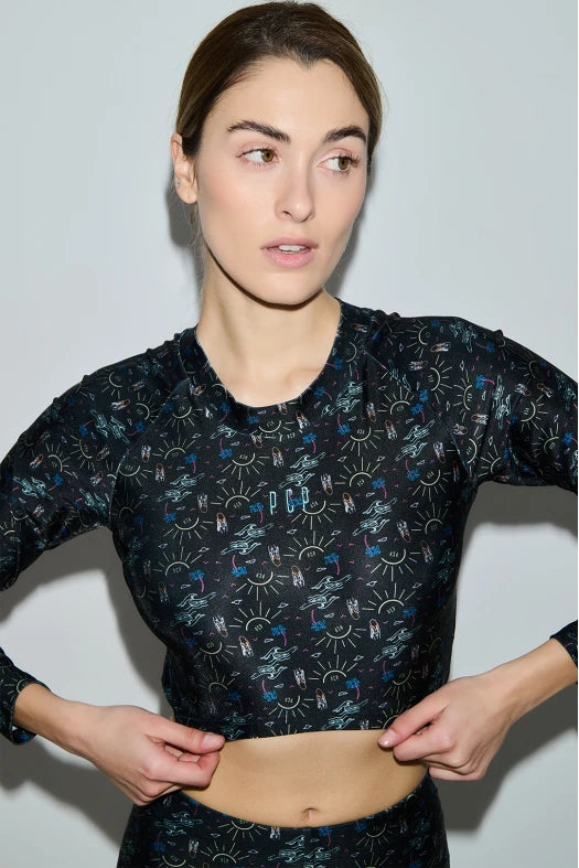 Woman wearing a black patterned long-sleeve top against a light gray background