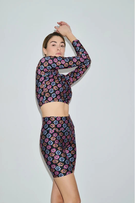 Woman wearing a colorful floral dress against a plain background