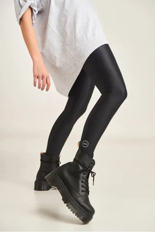Person wearing black leggings and black boots on a plain background