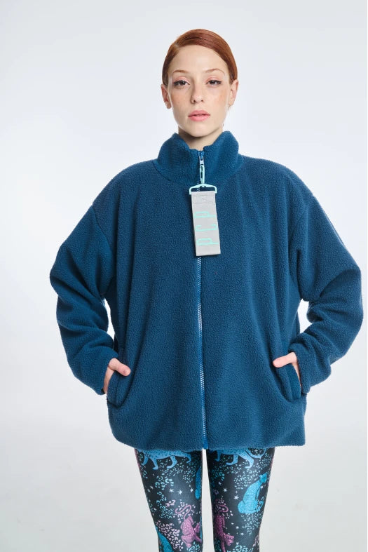 Person wearing a blue fleece jacket with a tag on a white background