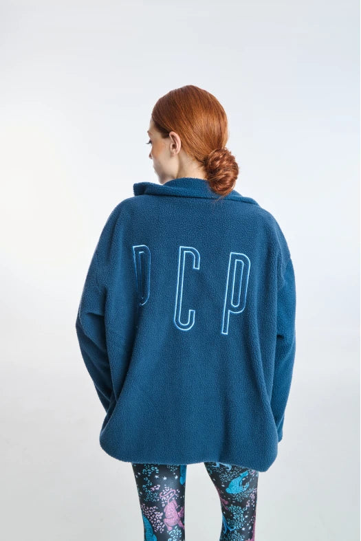 Person wearing a blue sweater with 'DCP' on the back against a white background