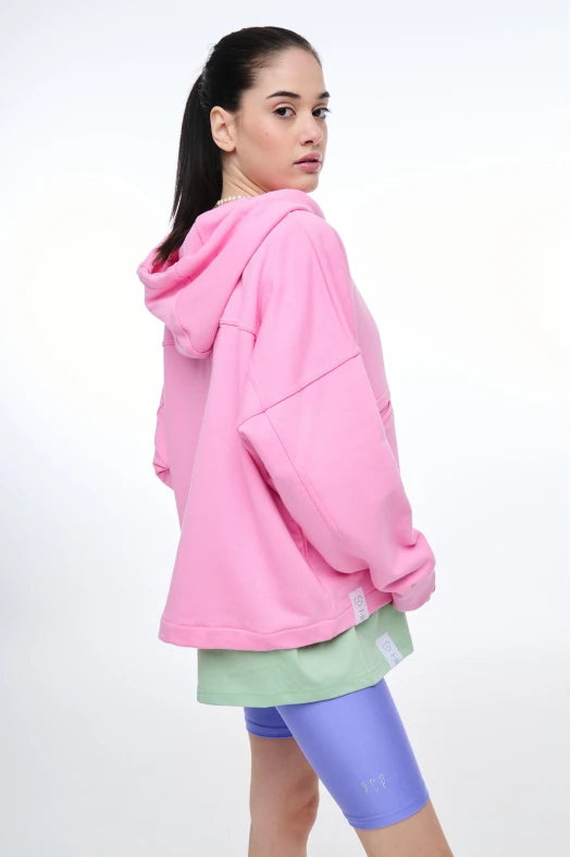 Person wearing a pink hoodie and colorful shorts on a white background